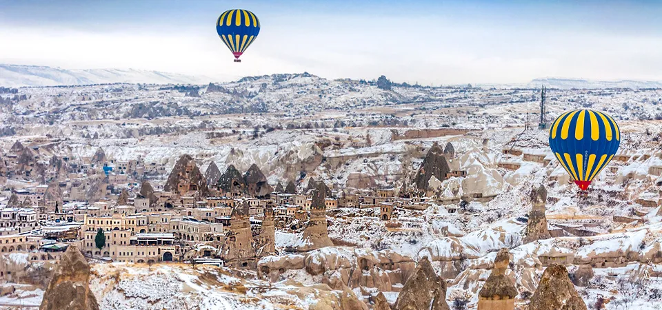 Hot air balloons over the snowy landscape of Cappadocia, Turkey